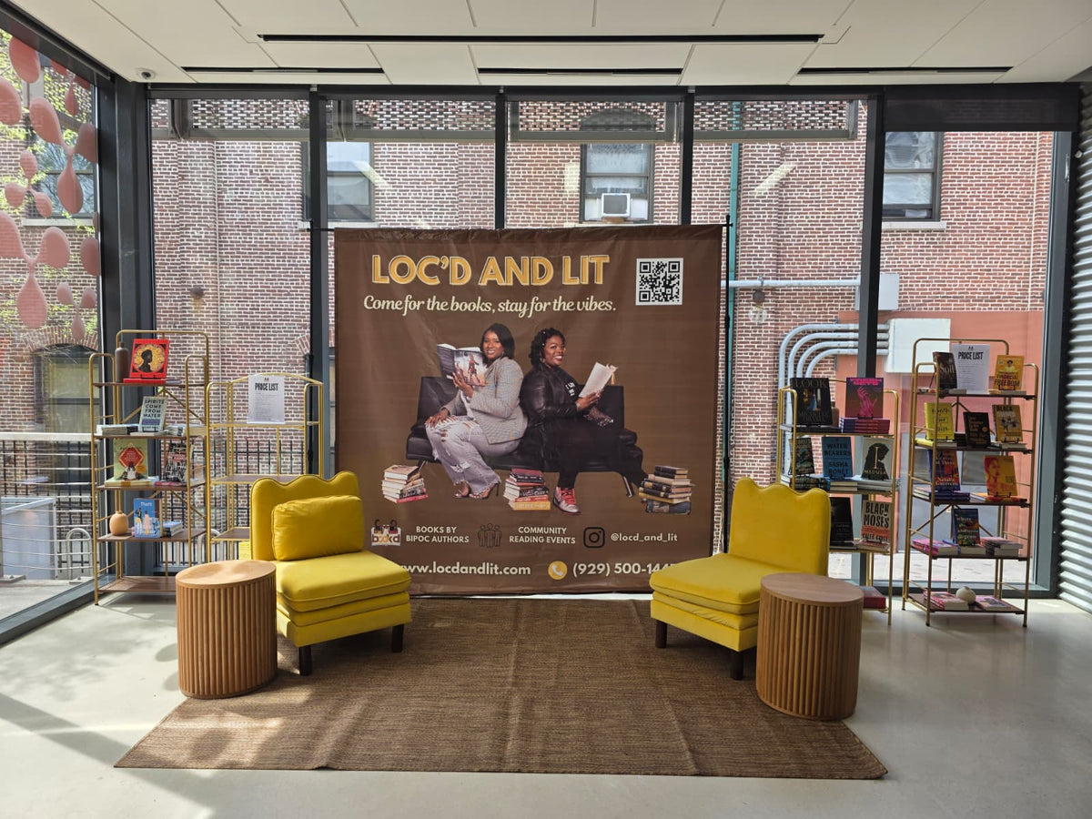 Loc’d & Lit display with bookshelves, two yellow chairs, and a banner.