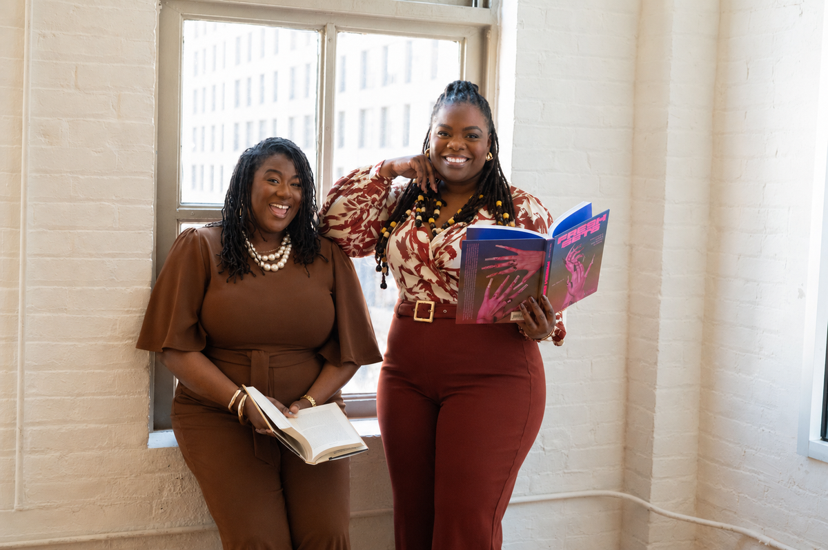 Two people smiling and holding open books.